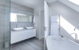 A serene and modern bathroom with clean lines, neutral tones, and minimalistic design elements. Features include a sleek sink, mirror, and wall-mounted fixtures.