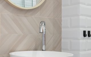 Bathroom scene with a sleek mirror, modern sink, vanity, and tiled backdrop